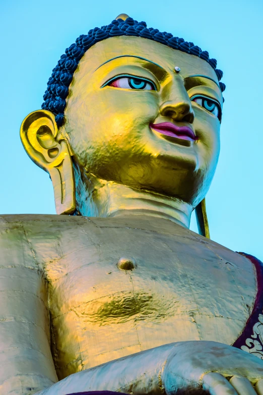 a golden buddha statue with a blue sky behind it