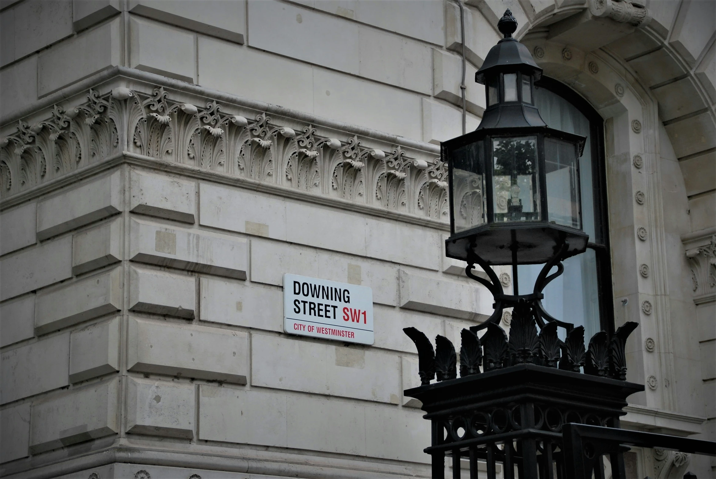 an iron gate that is attached to a lamp on the side of a building