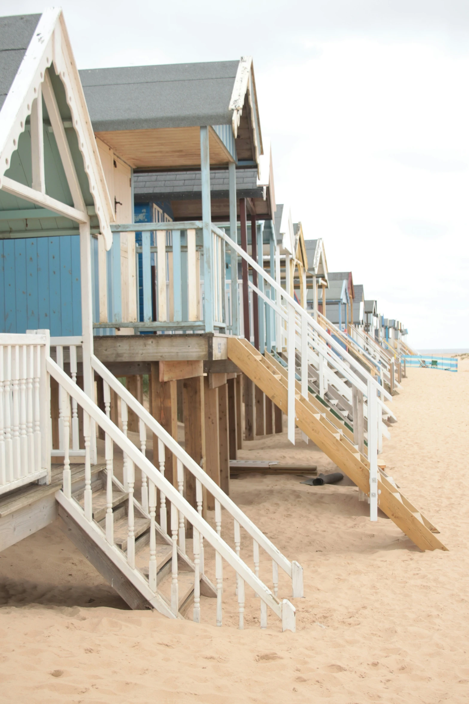 wooden stairs lead up to the beach as a building on the side looks out to sea