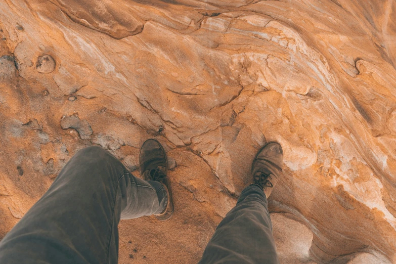 man standing on the edge of a brown colored rock