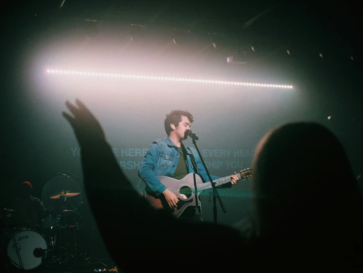 a man holding his hand up and playing a guitar