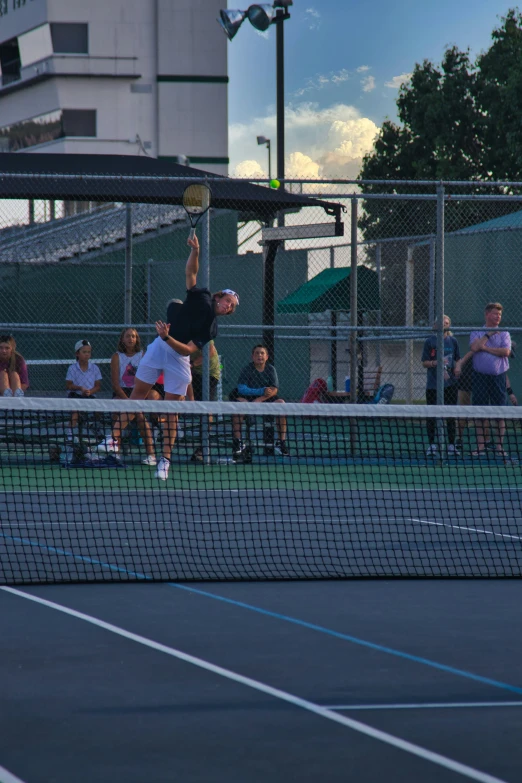 tennis court with people on the sidelines watching and others sitting around