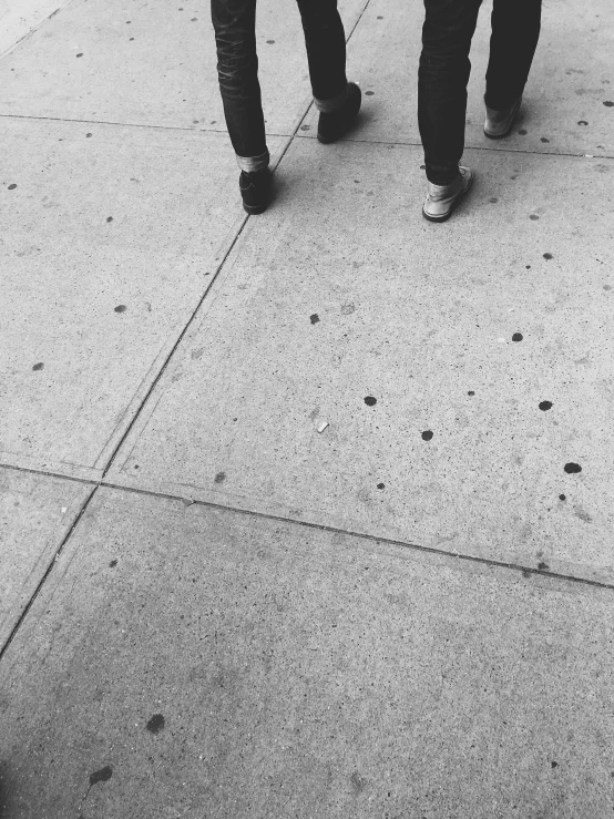 a couple walking down the street and looking towards soing on the sidewalk