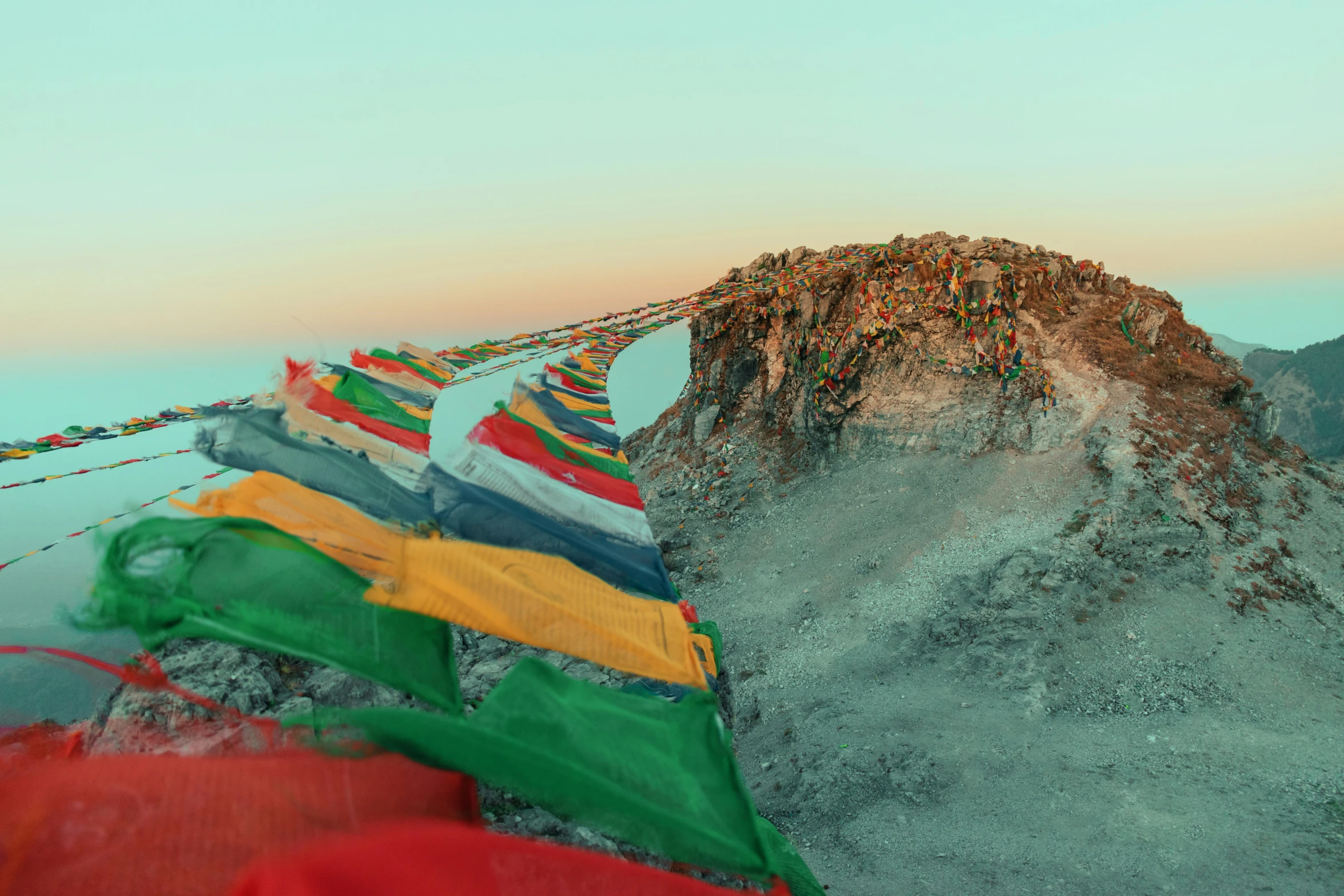 a row of brightly colored flags next to a rocky hillside