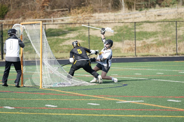 a lacrosse player is blocking the ball while others are watching