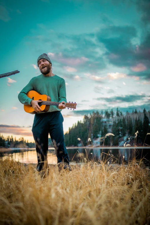 a man is standing in a field with his guitar