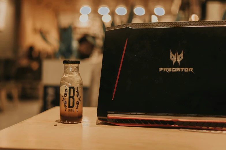 a black laptop computer next to a beer bottle