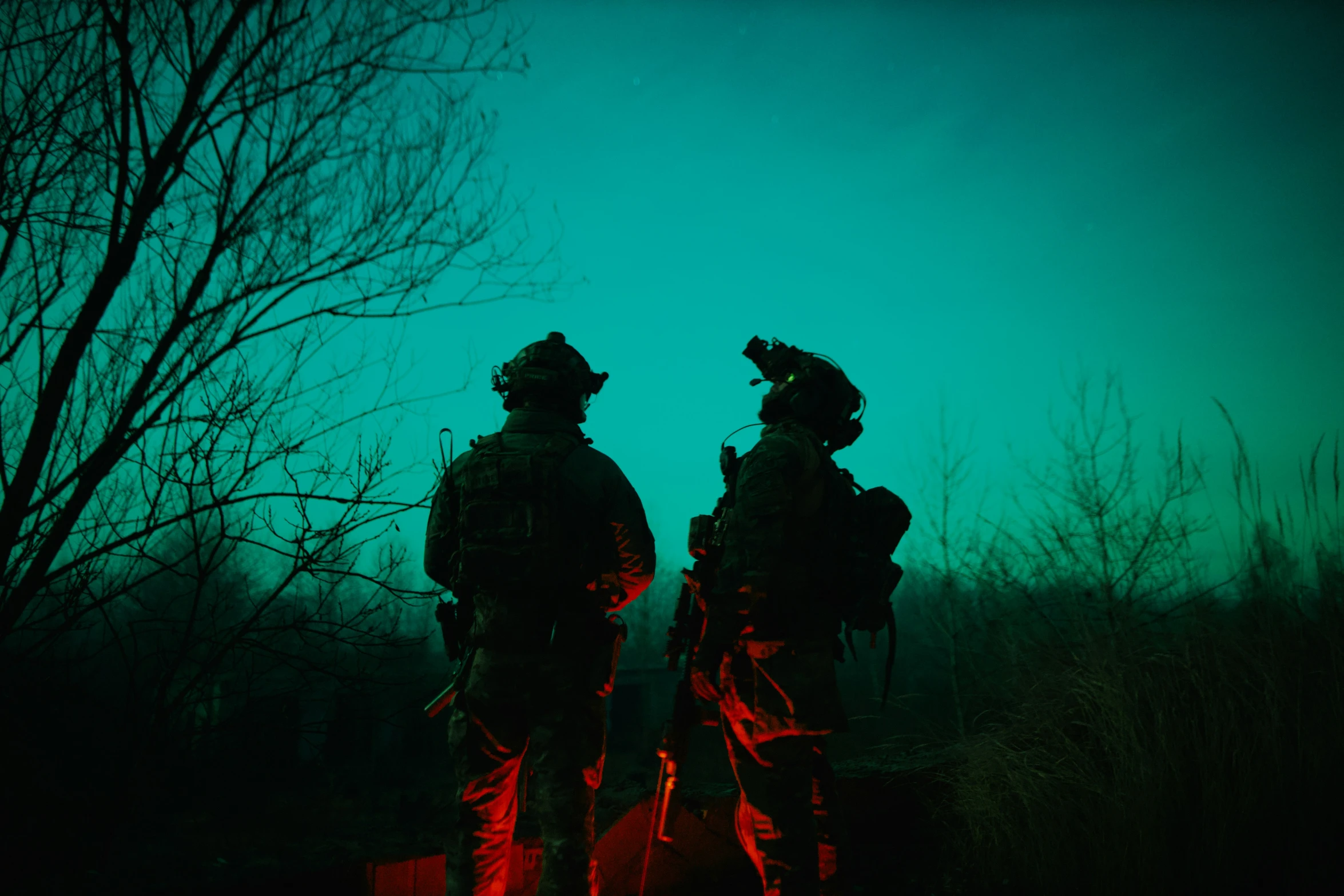 two men standing in front of a dark green sky with the lights on