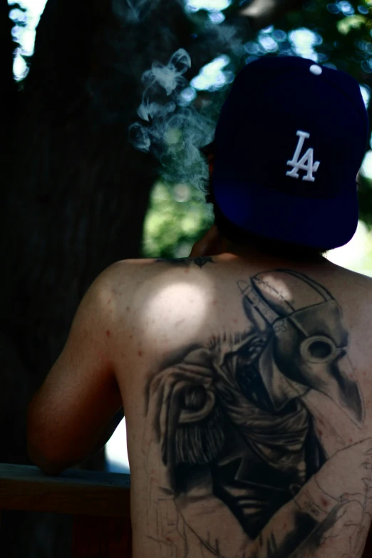 a man with a tattoo on his back looks through the woods