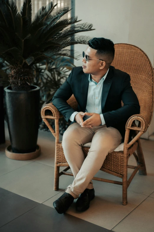 a man sitting in a chair with a plant next to him