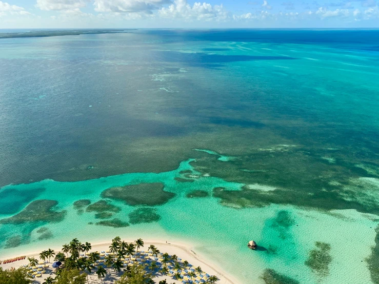 a small boat is on the water near some sand and palm trees