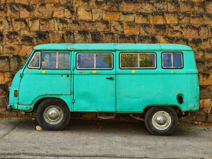 a blue van parked in front of a brown brick wall