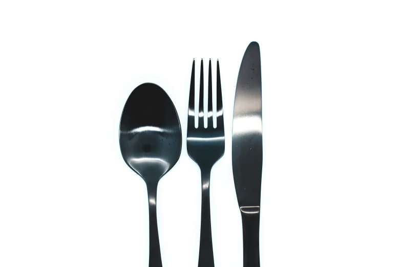 a silver fork and knife and spoon on a white surface