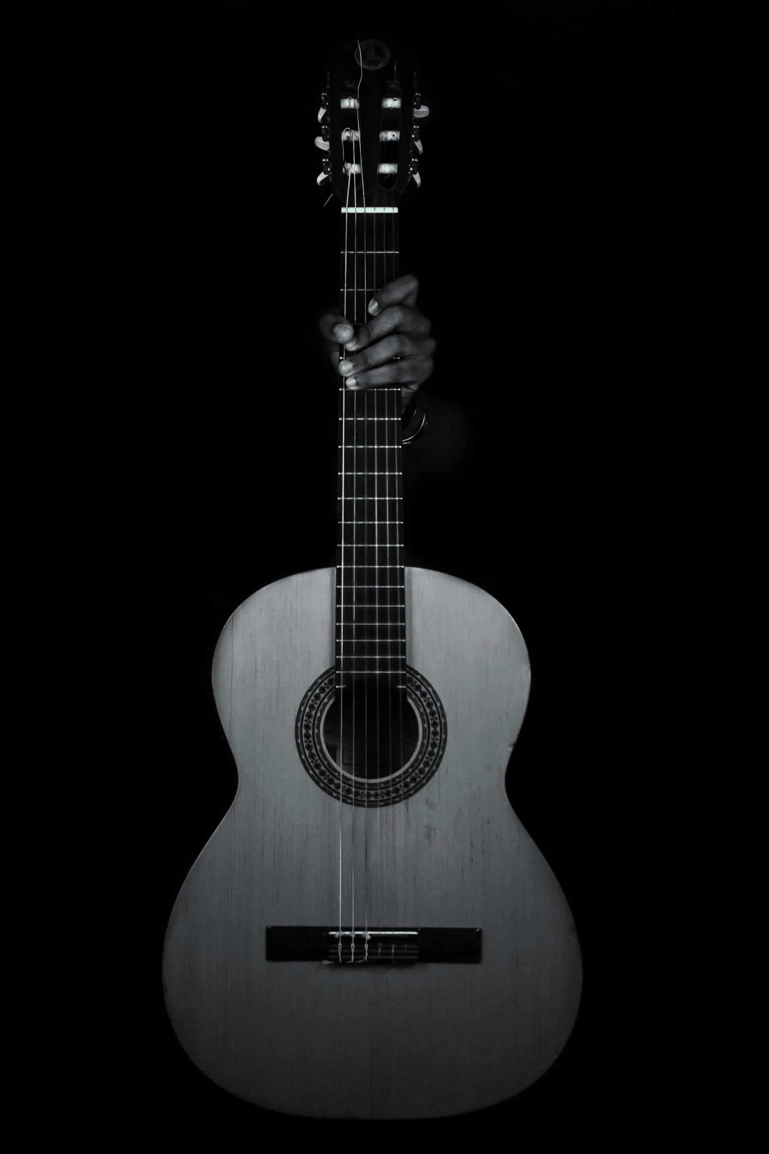 an acoustic guitar is held up in the dark