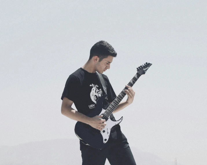 a male playing a guitar on the beach