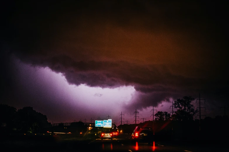 storm clouds loom in the sky above cars at night