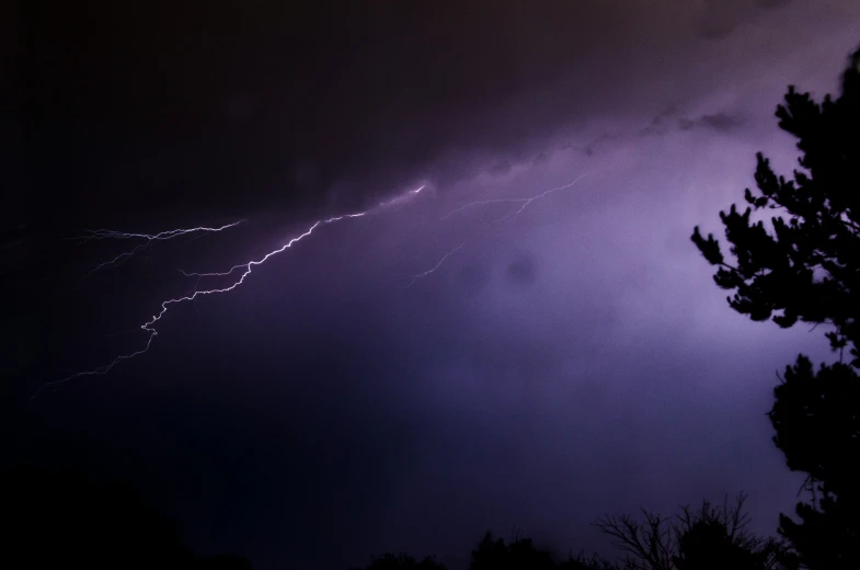 the dark sky is filled with lightning and some white clouds