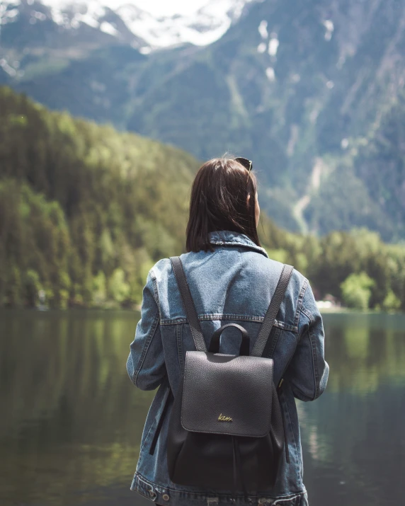 the back of a woman walking near water in a valley