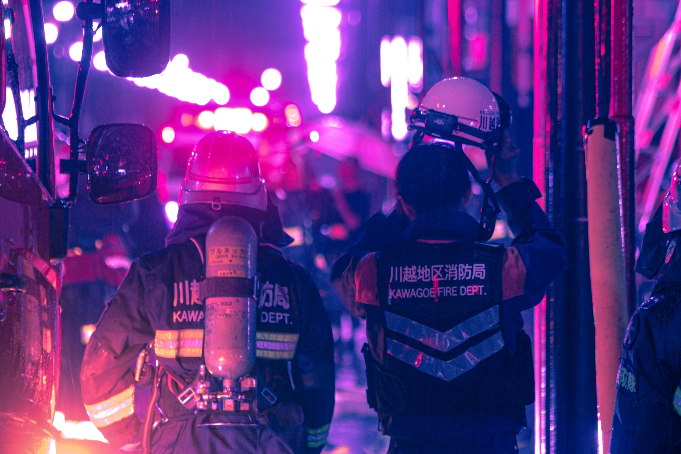 two firemen on the side of a street at night