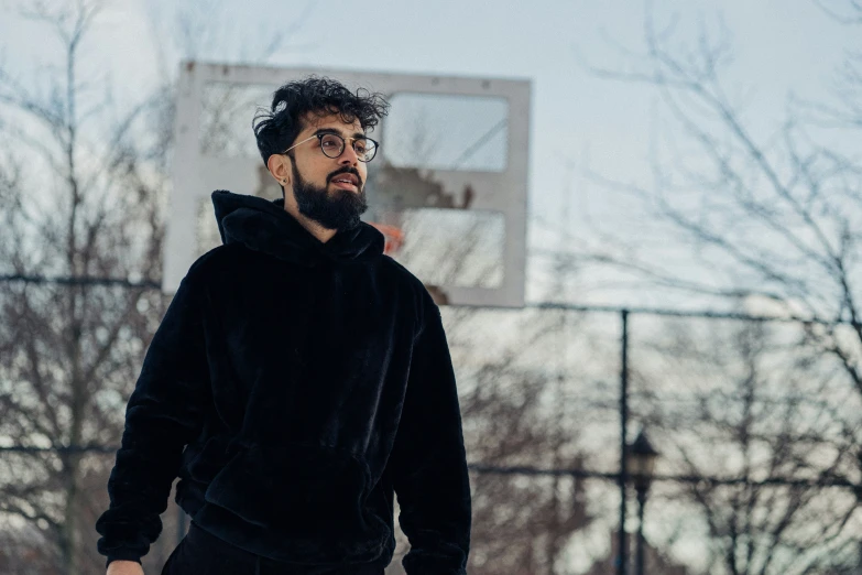 a young man wearing a hoody playing basketball