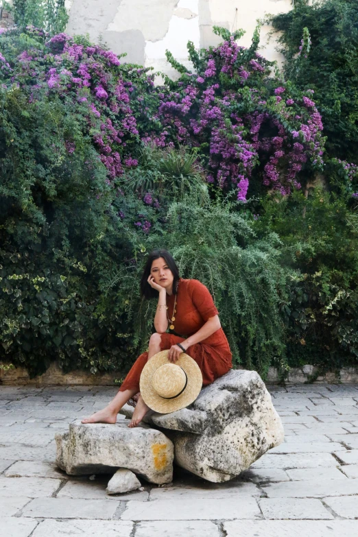 the woman is sitting on a rock near some trees