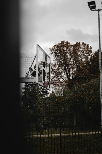 a basketball goal in a park under cloudy skies