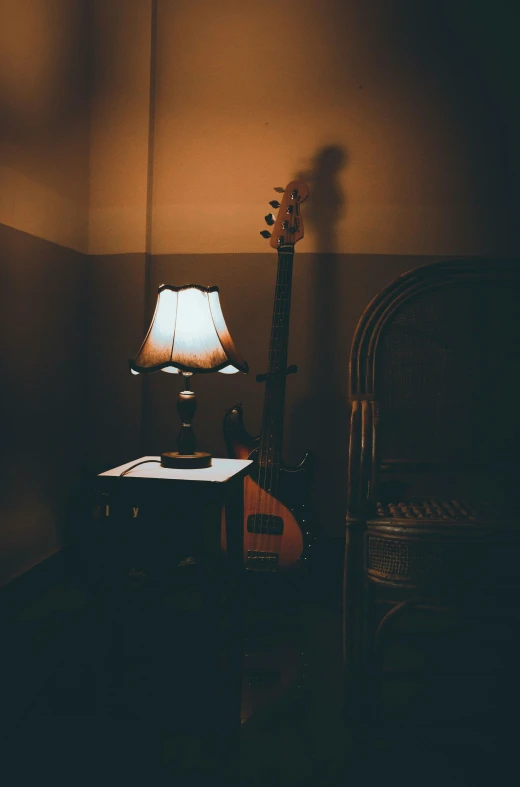 a guitar sits in front of an illuminated lamp