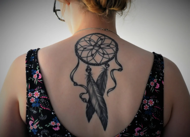 a woman with a large black and grey feather dream catcher on her back