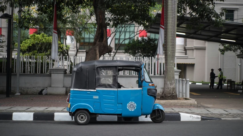 a blue small three - wheeled vehicle on the road