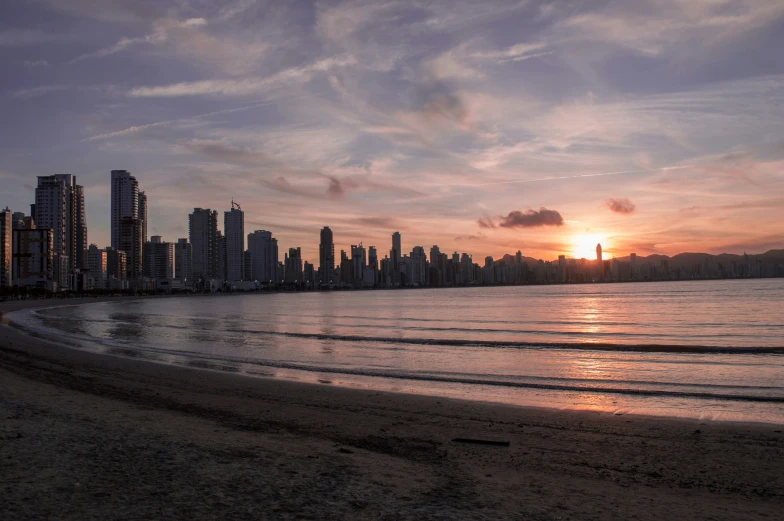 a surfer is seen silhouetted against the backdrop of a city skyline