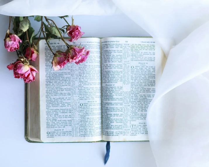 an open book on a white table with some flowers