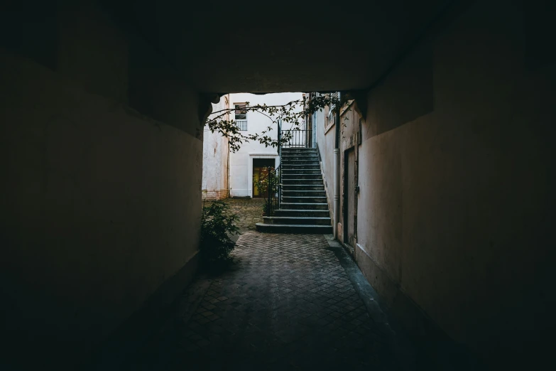 a dark alley way with steps leading to a house