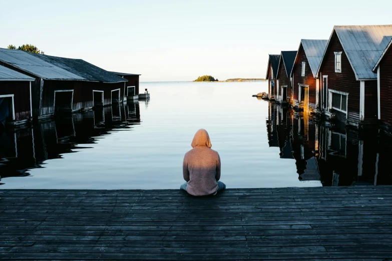 a girl sitting on a dock looking out into the water