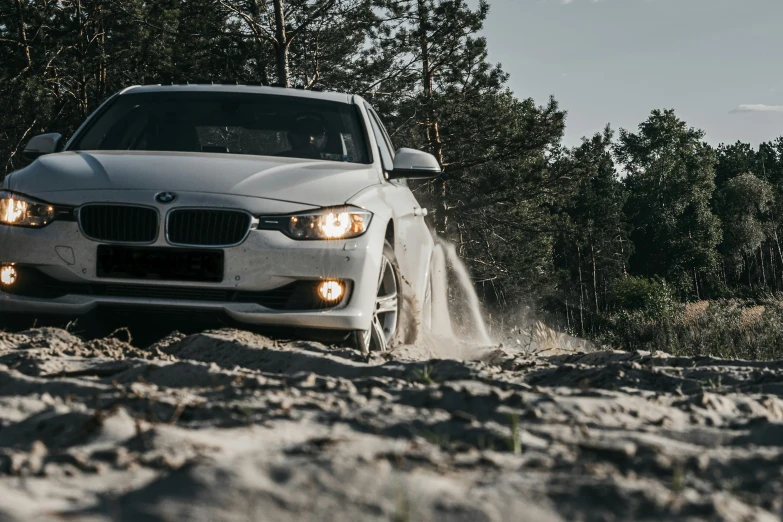 a car is driving on the sand near some trees