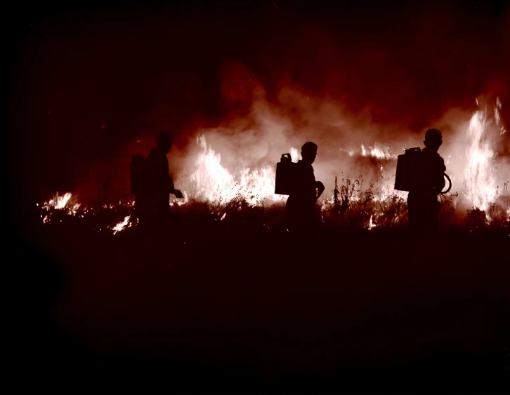 several people standing around a fire in the night