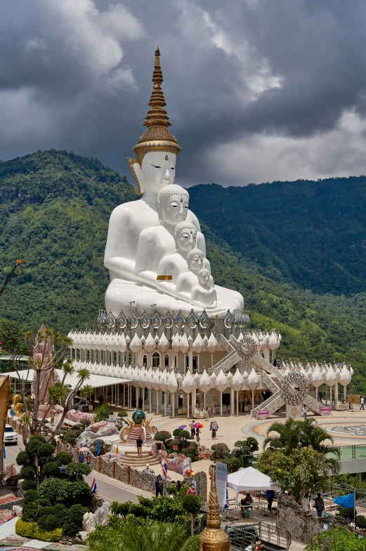 large white buddha statue sitting on top of a building