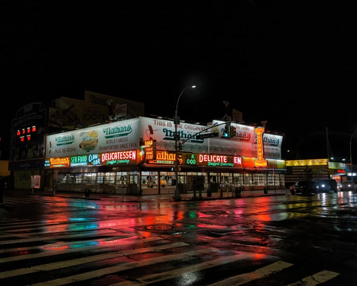 an outdoor cafe sitting next to a road with a lot of neon signs on the side