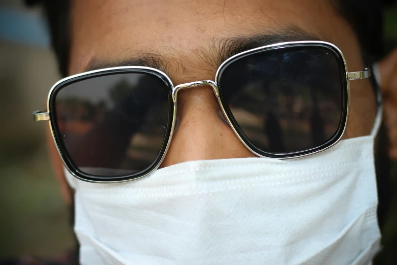 a man wearing sunglasses and a white face mask