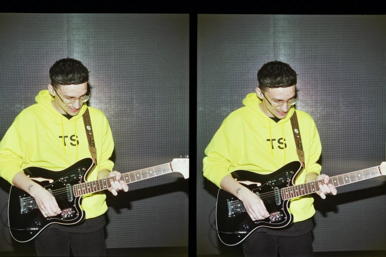 a guy with a yellow sweatshirt playing guitar