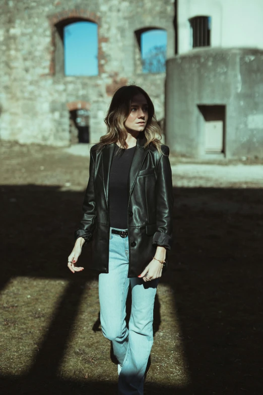 a young woman walking down a dirt road next to a building