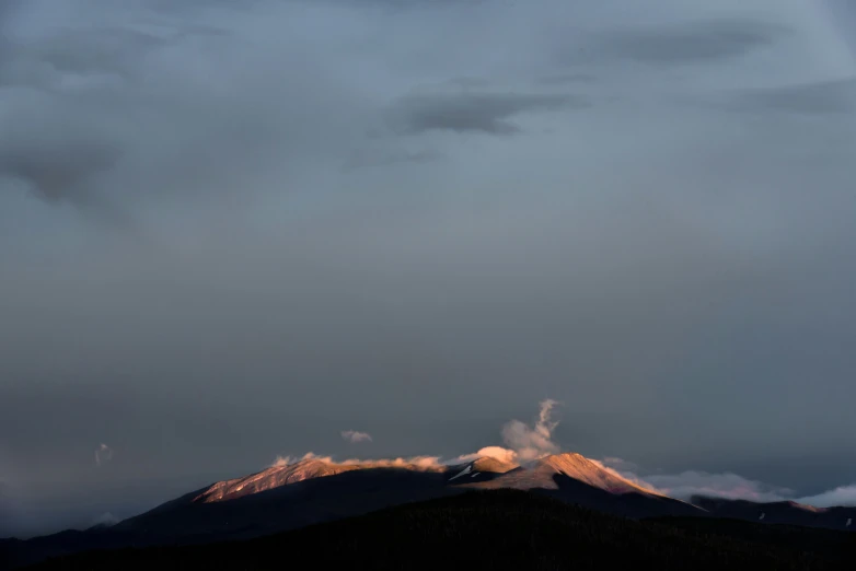 the snow covered mountain tops glow orange at dusk