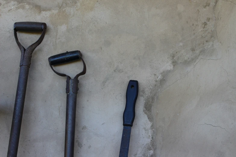 three different garden tools lined up together on concrete