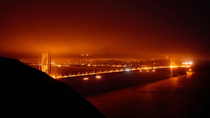 the city lights are on as fog hangs above