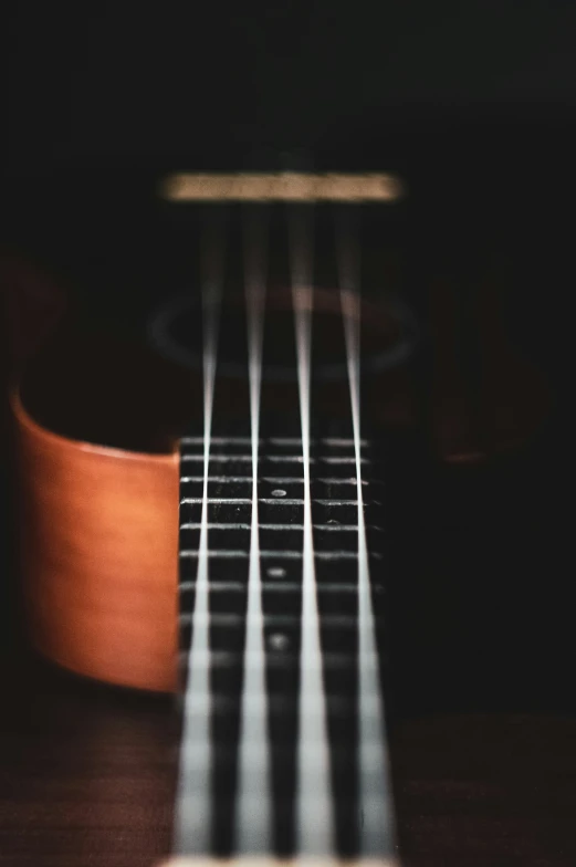 the strings on an acoustic guitar sit in front of a black background