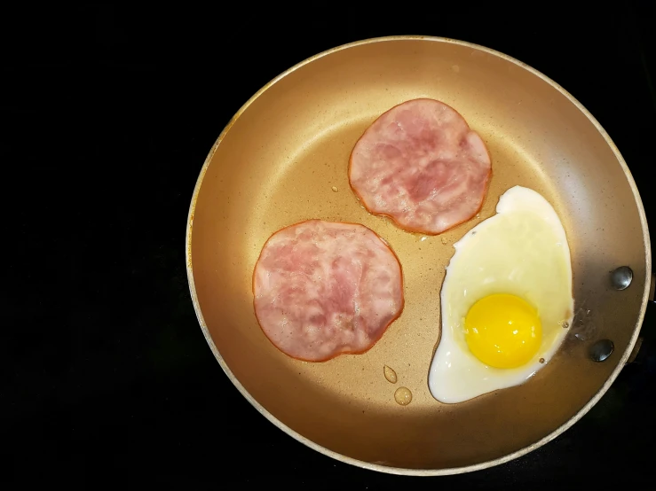 two cooked sausages and an egg are in a frying pan