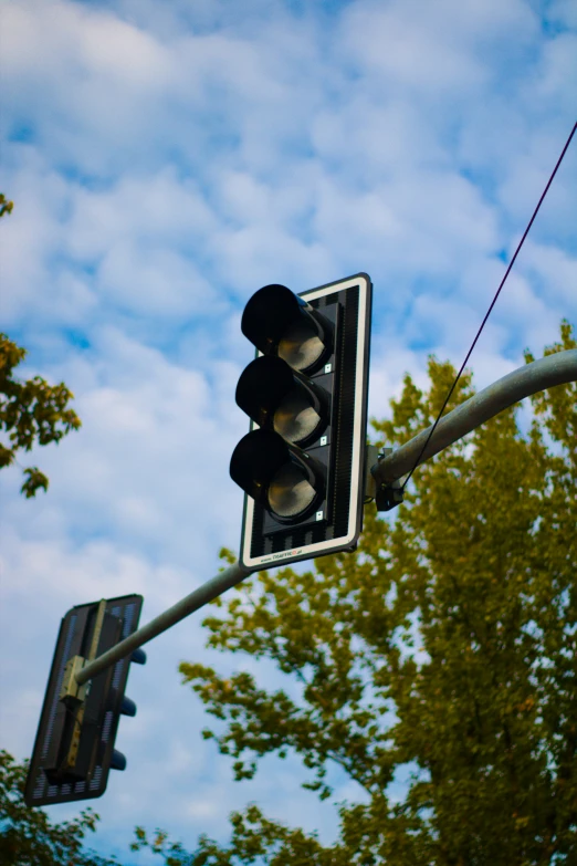 a stoplight attached to a traffic pole next to some trees