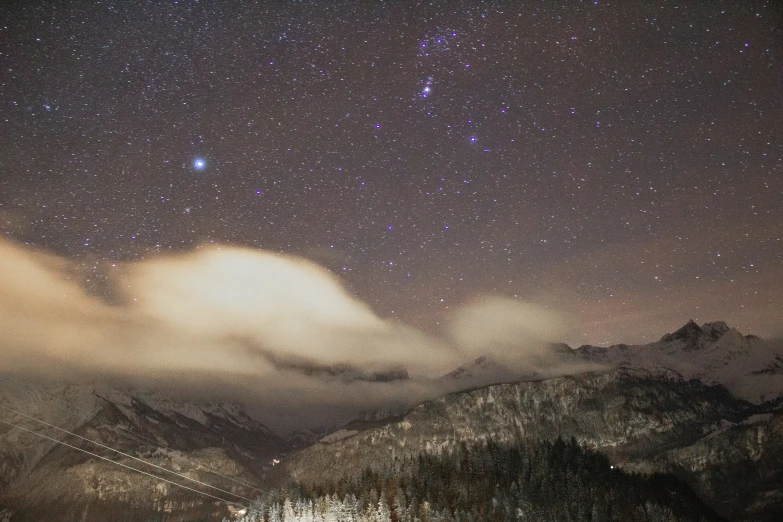 the night sky and stars above some mountains
