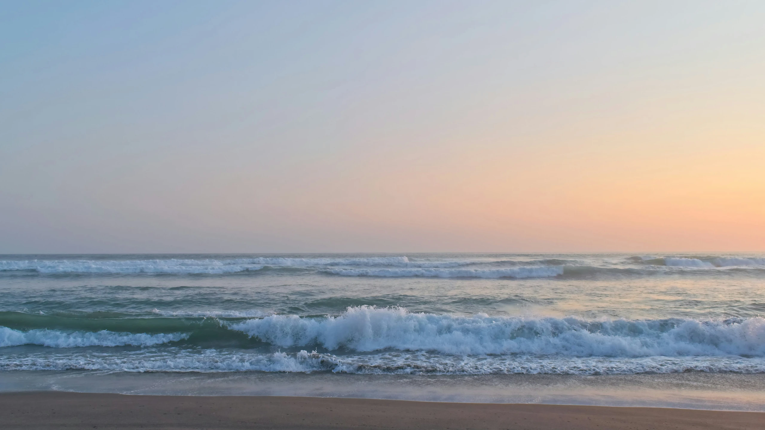 an ocean view with waves rolling in to shore and the sun reflecting off of the water