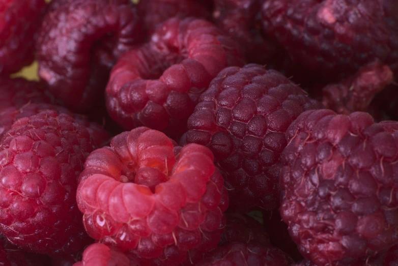 a pile of fresh raspberries is in the middle of a bowl