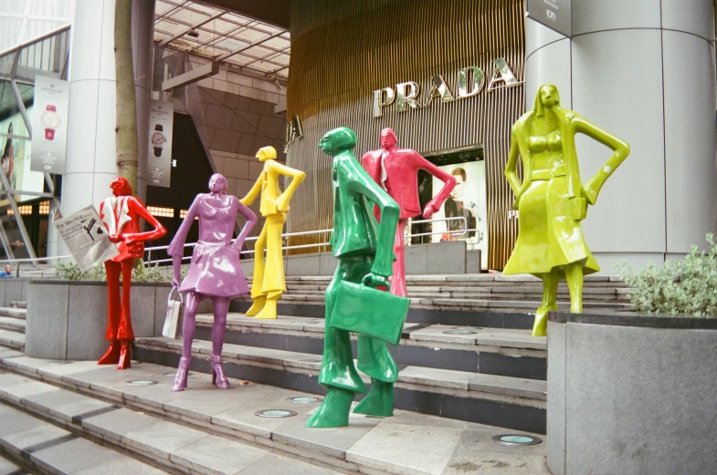 sculptures of people in various colors, sitting on steps